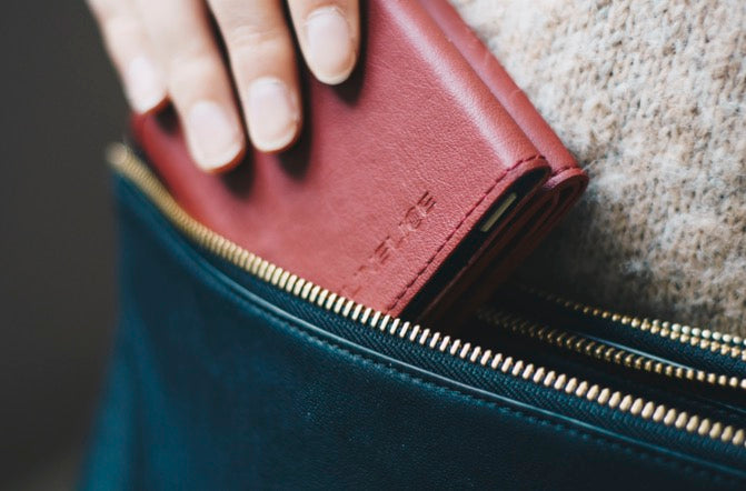 female hand slipping a red solar charger into her bag