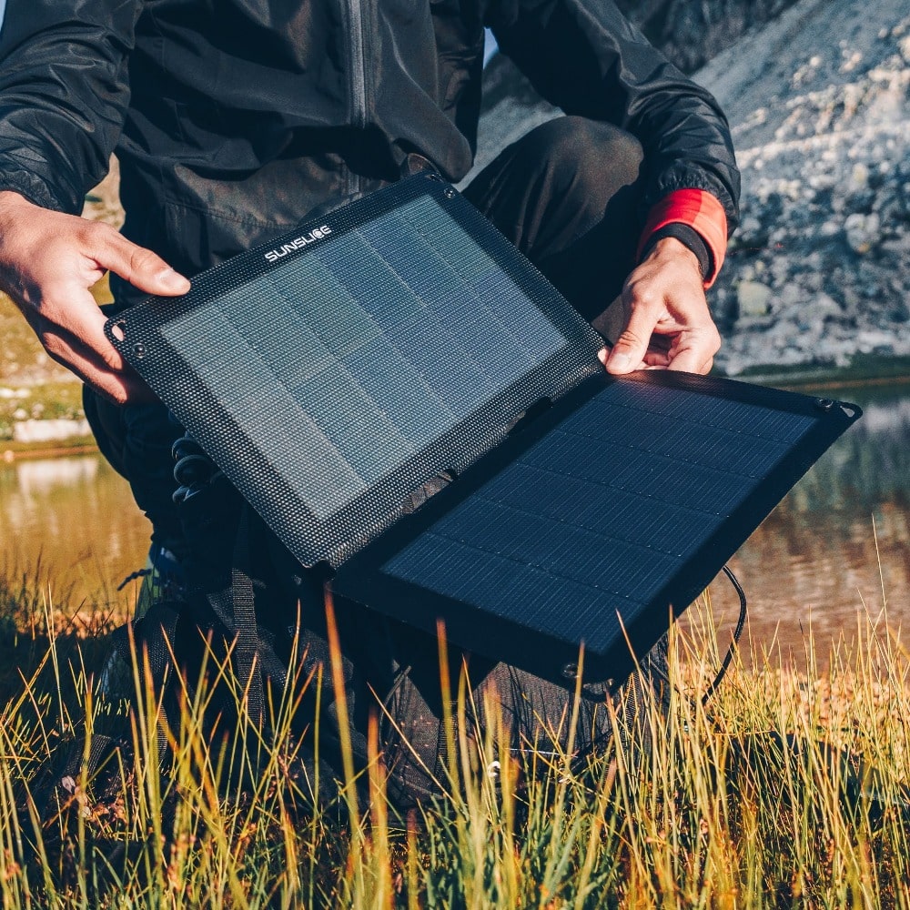 man carrying the best portable solar panel on a mountain