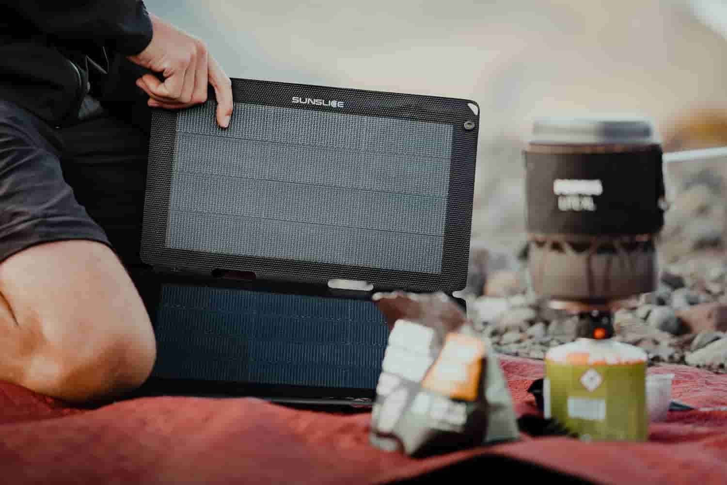 man packing up his professional photography equipment and using a compact solar panel outdoors