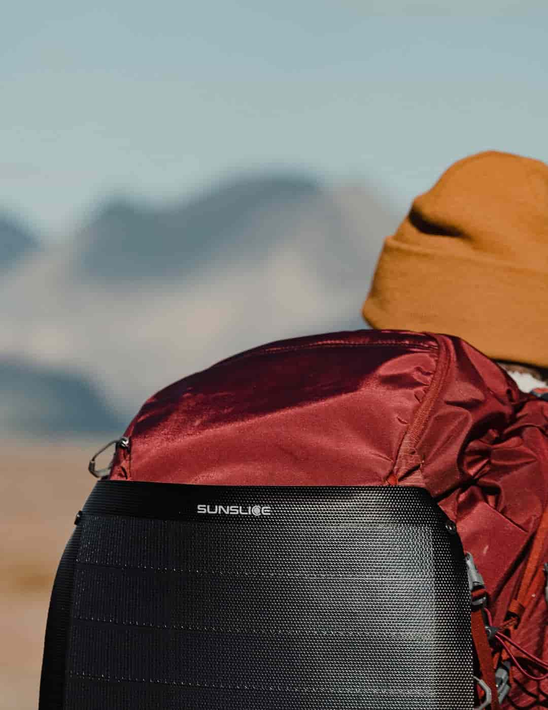 sac de randonnée rouge avec un panneau solaire pliable attaché et bien exposé au soleil