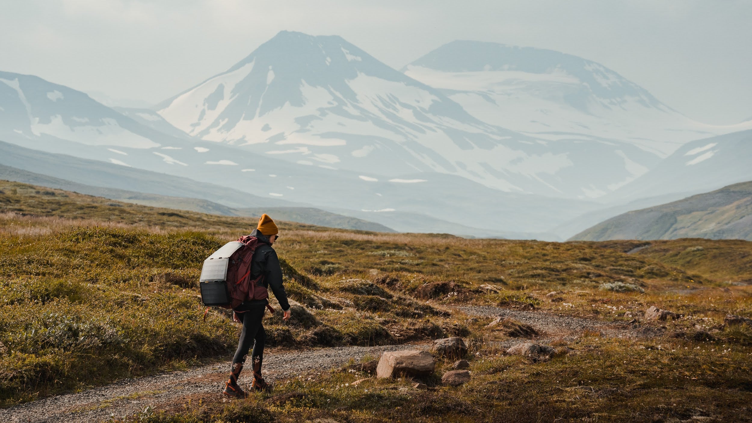 woman walking with a hiking solar panel attached to her backpack