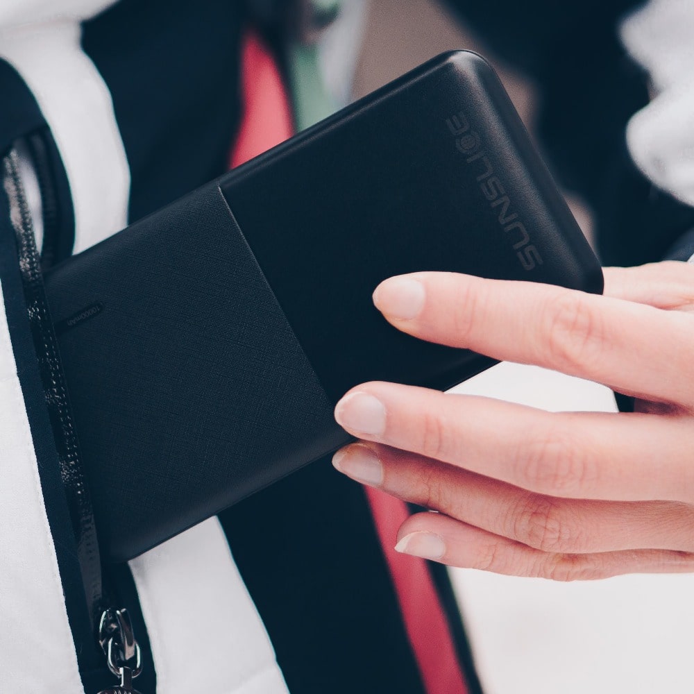 hand of a woman putting a solar power bank charger in her bag