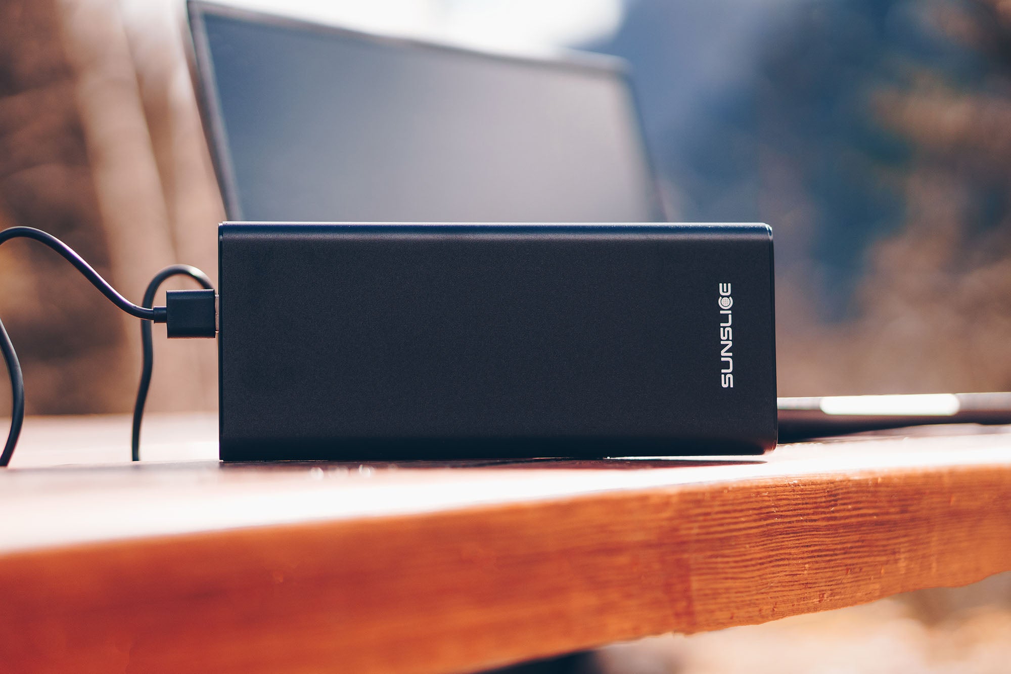 Sunslice 100W Power Bank auf einem Tisch mit einem Laptop dahinter