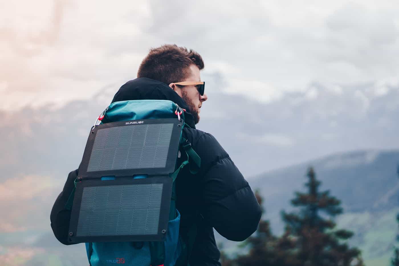 man carrying the best portable solar panel on a mountain