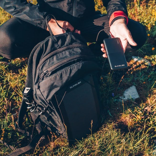 photo prise à l'extérieur avec un homme qui branche la batterie de son panneau solaire