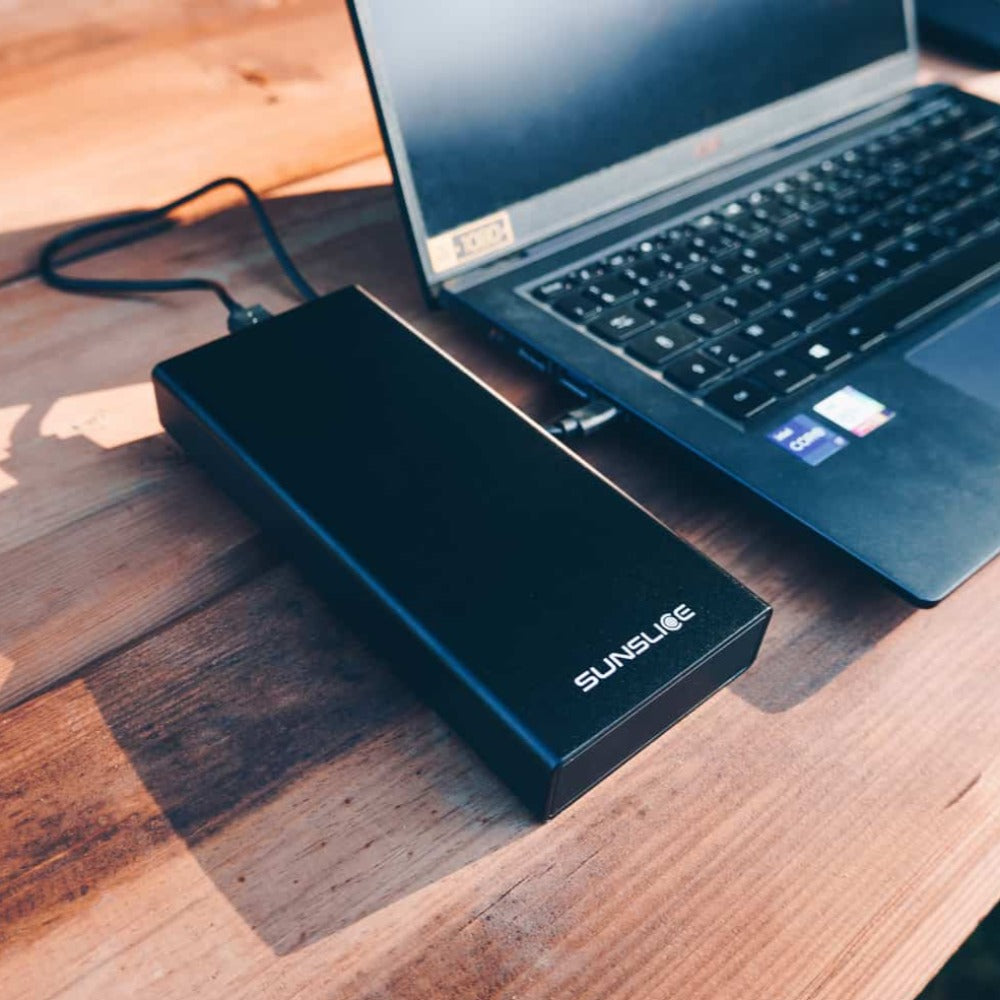 tragbares Laptop-Ladegerät, das einen Computer auf einem Tisch im Freien auflädt