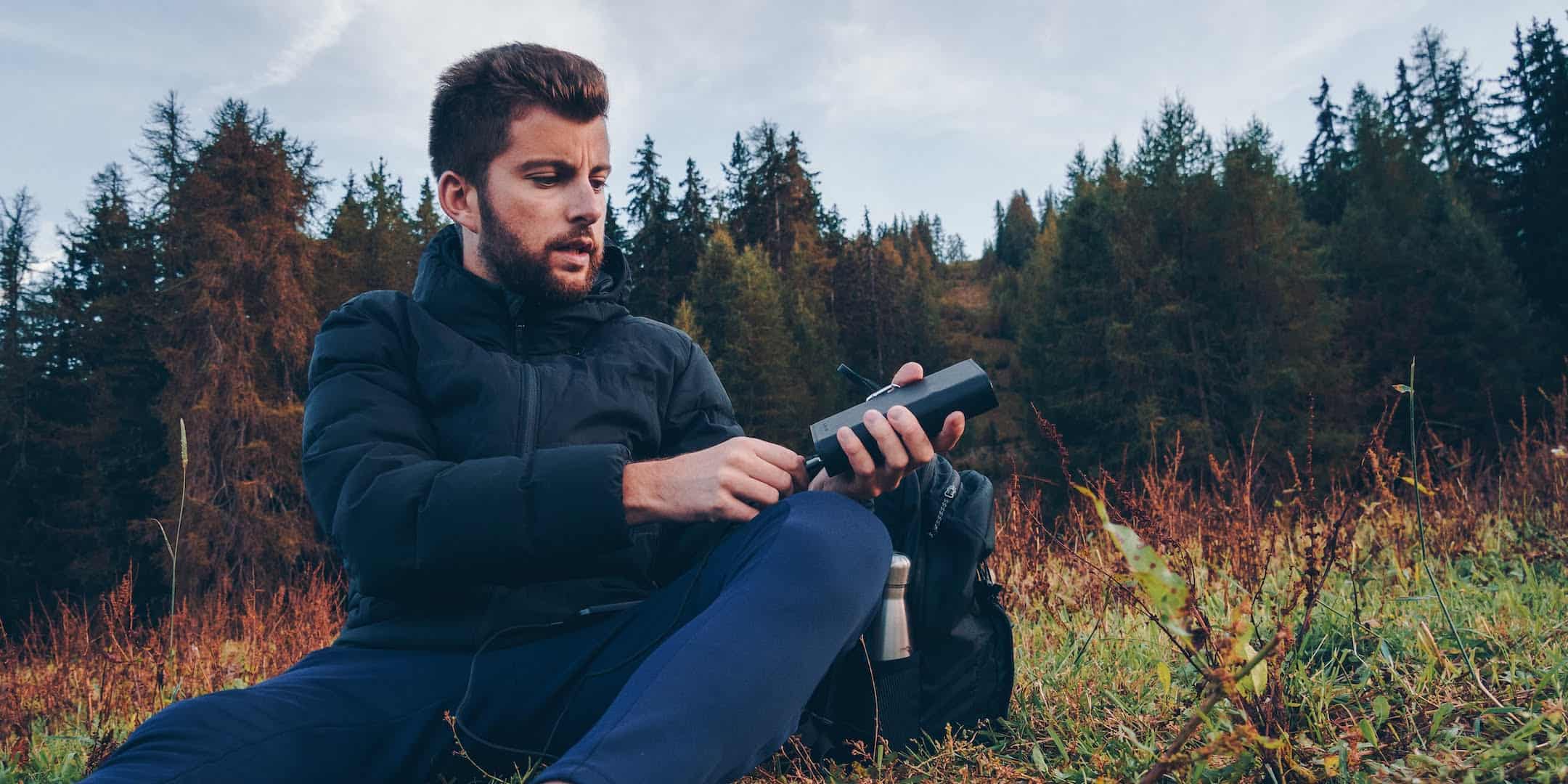 Sunslice Electron zonne-energiebank laadt de smartphone van een man op tijdens het kamperen