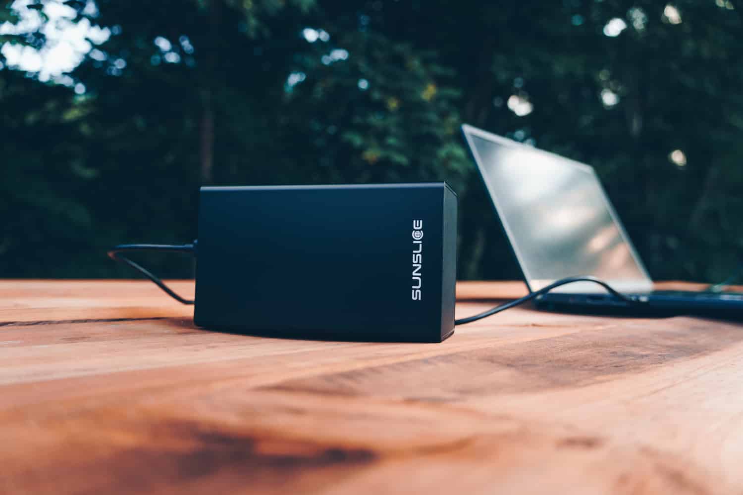Batterie Externe de 100 watts/heure rechargeant un ordinateur sur une table en plein air