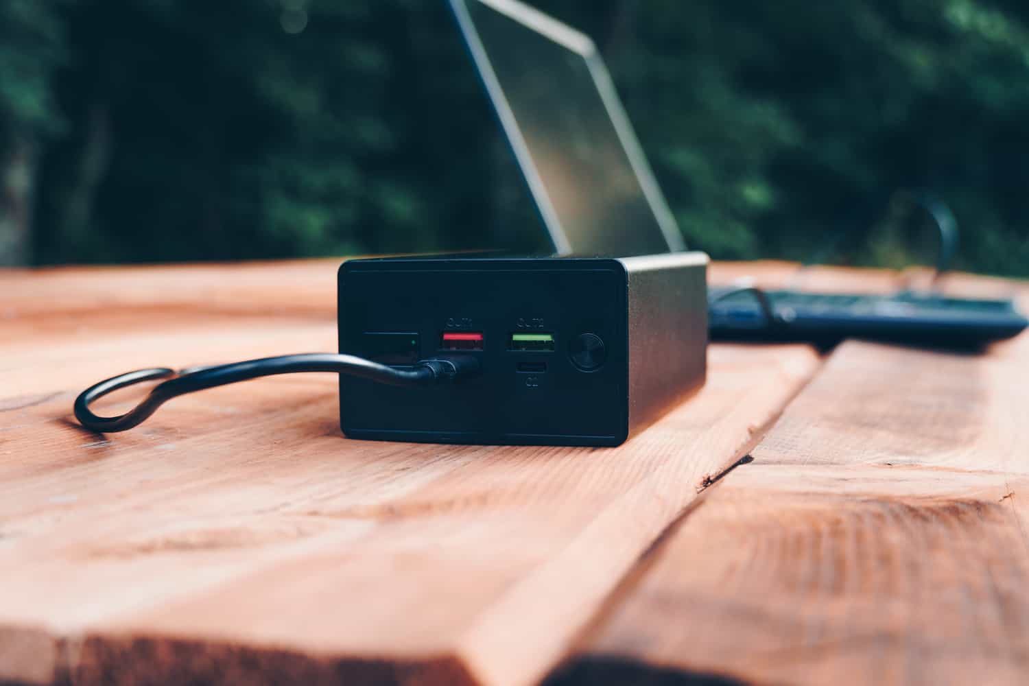 portable laptop charger charging a computer on an outdoor table