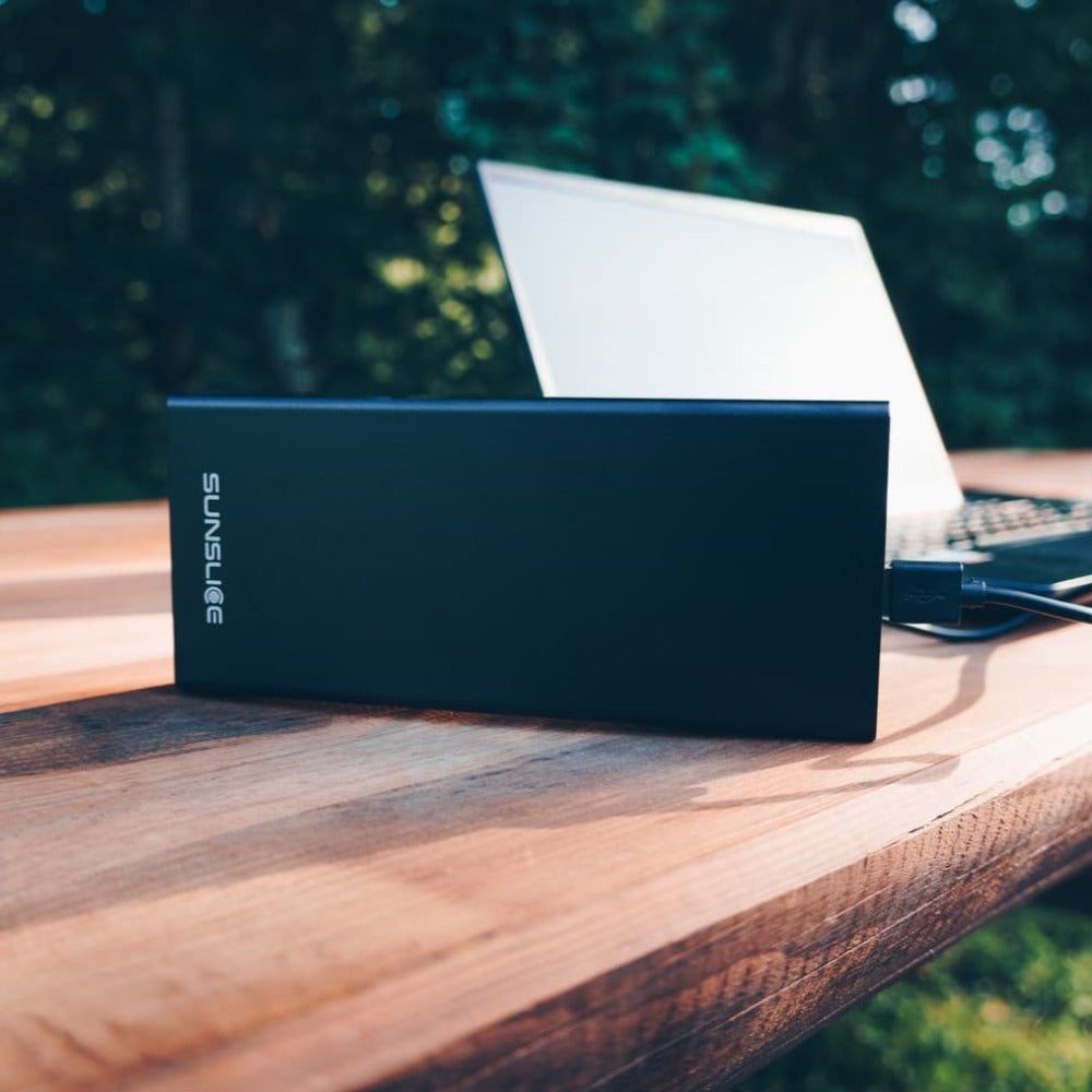 tragbares Laptop-Ladegerät, das einen Computer auf einem Tisch im Freien auflädt