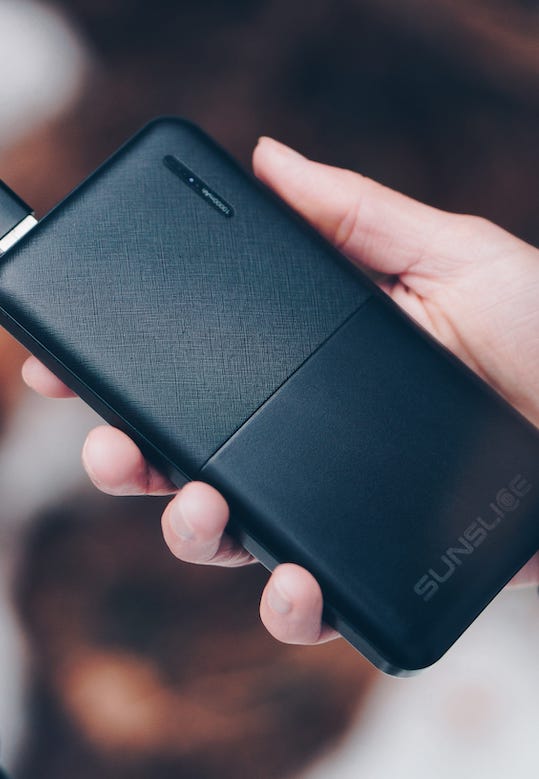 Main tenant un Powerbank 10000mAh chargeant un smartphone
