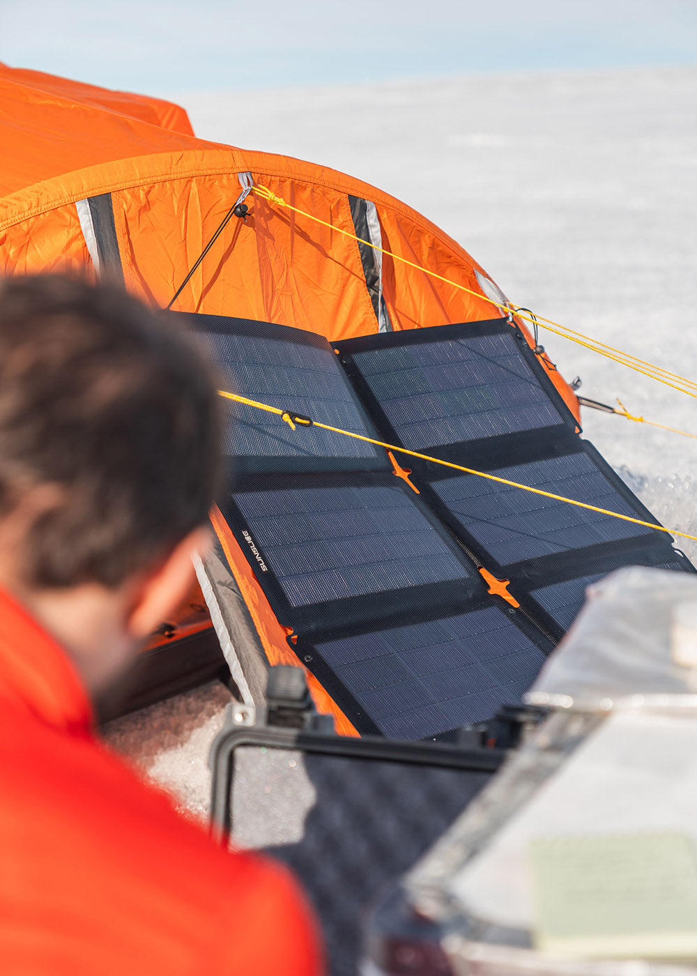 Focus sur un panneau solaire ( Fusion flex 48) sur une tente avec un homme à l'avant qui le regarde.