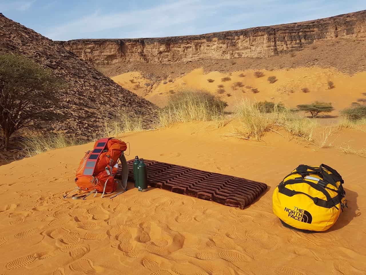 hiking bag on sandy ground with a Photon solar power bank charger attached to it