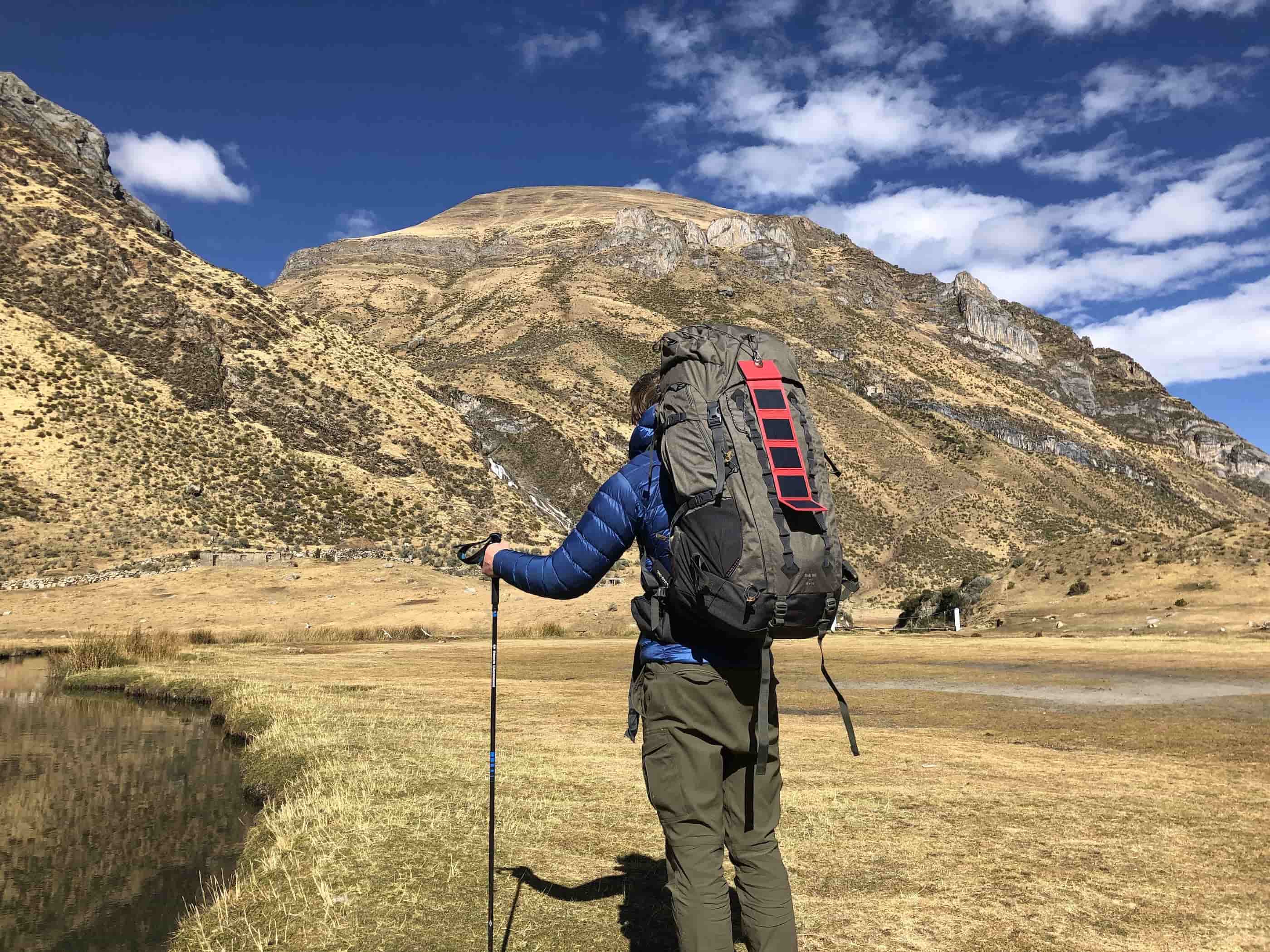 a man about to climb a mountain with a hiking backpack and a solar power bank charger attached to it