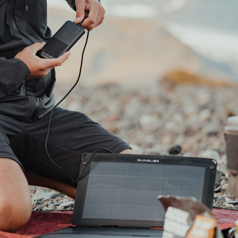 Mann, der das beste tragbare Solarpanel auf einem Berg trägt