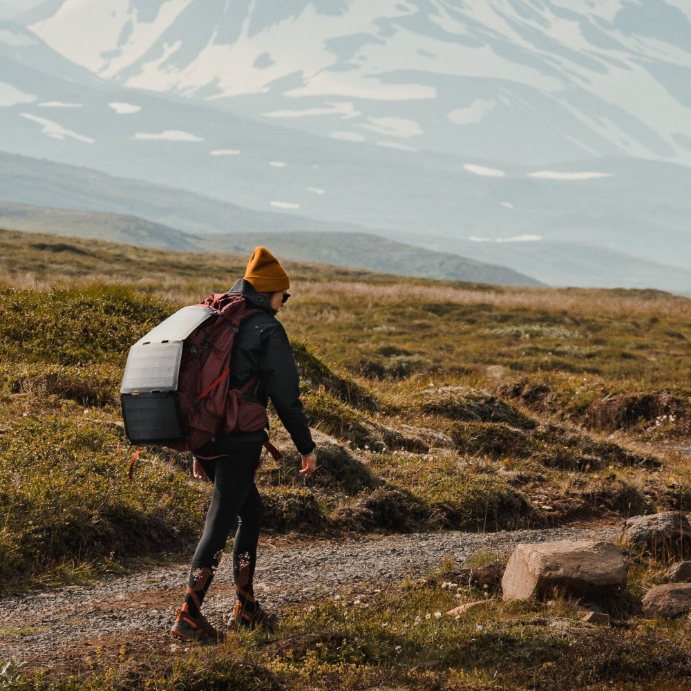 woman walking with a hiking solar panel attached to her backpack
