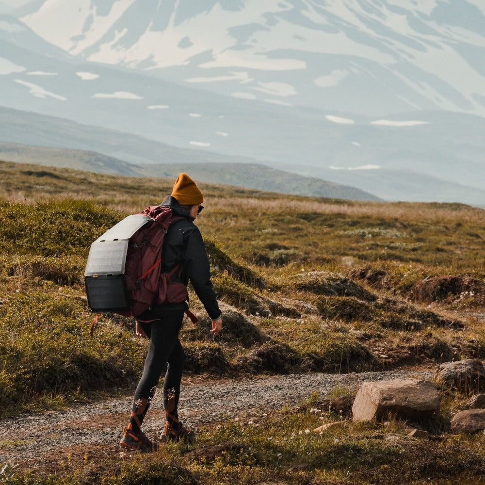 Frau, die mit einem an ihrem Rucksack befestigten Solarpanel wandert