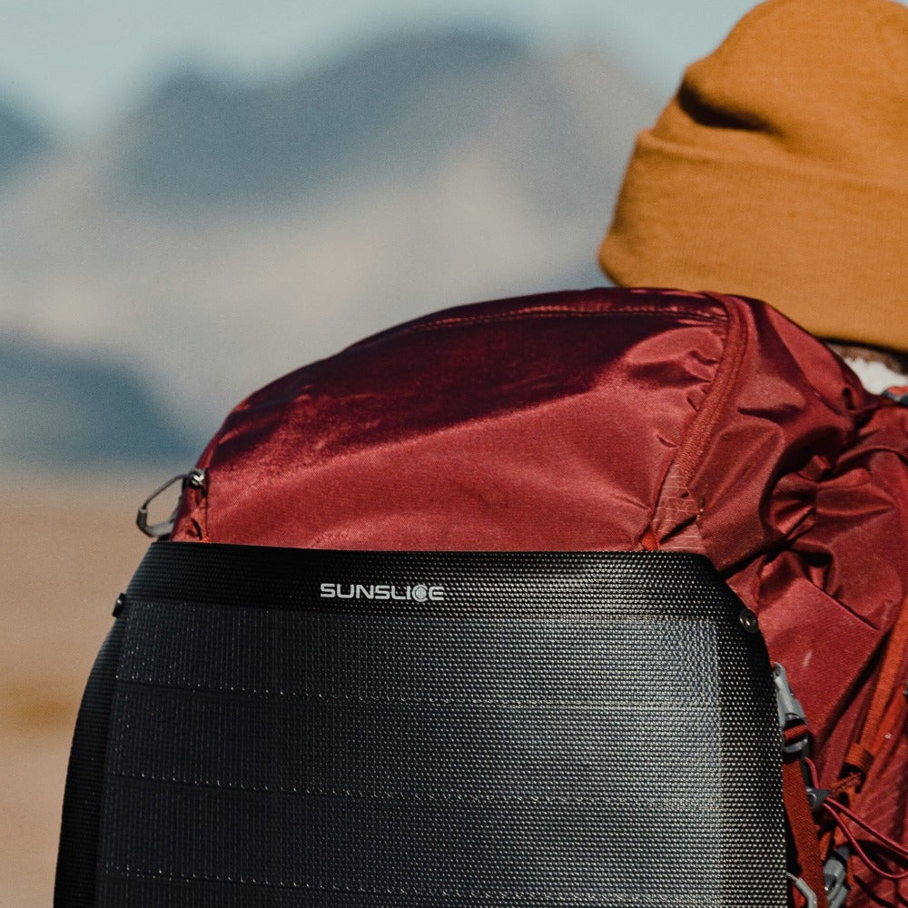 red hiking bag with a foldable solar panel attached and well exposed to the sun