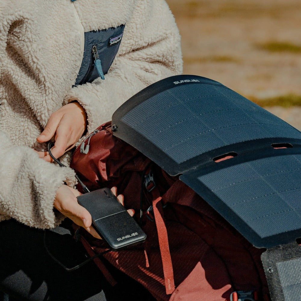 female hand slipping a red solar charger into her bag