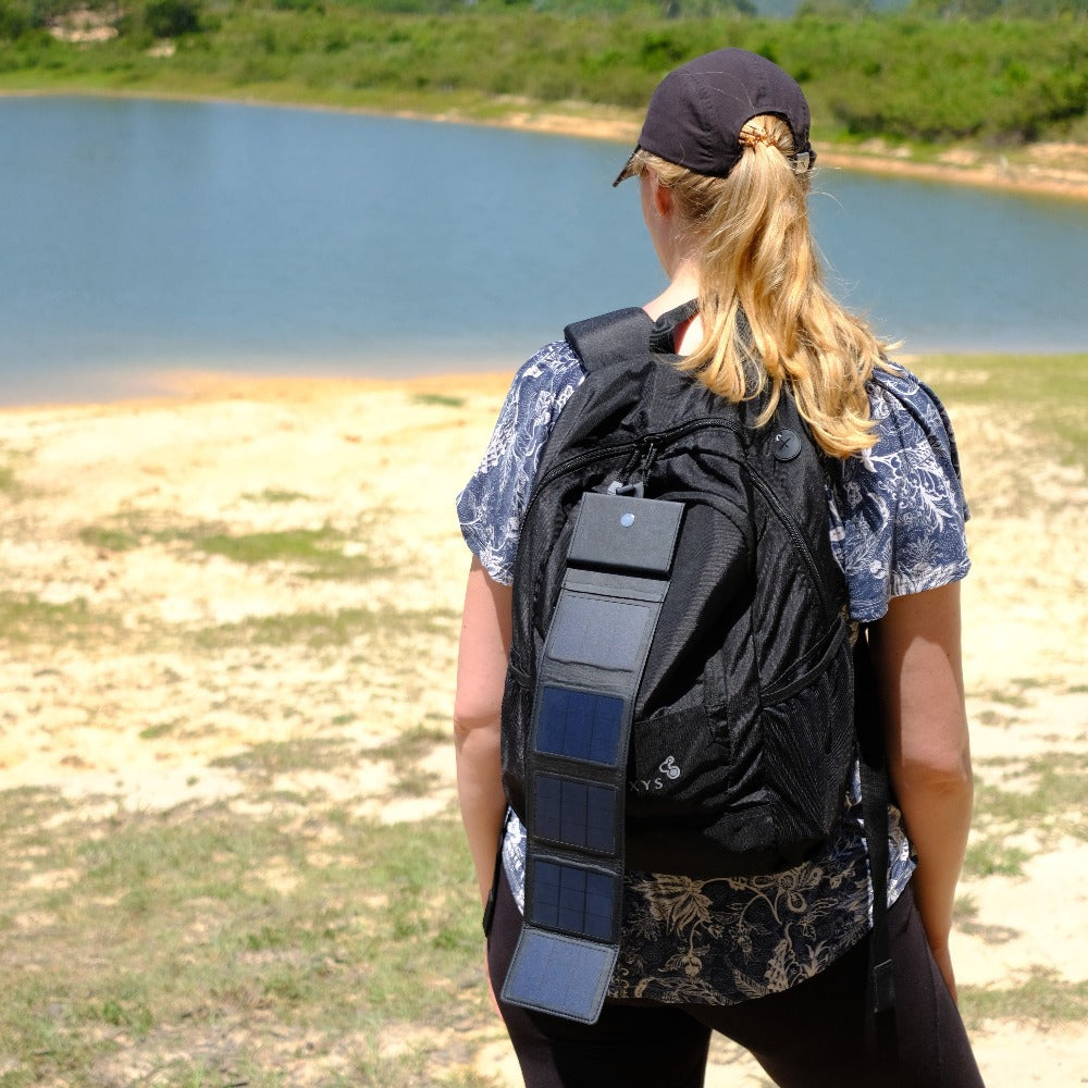 Photon - woman holding a solar panel for camping in the sun, seen from behind