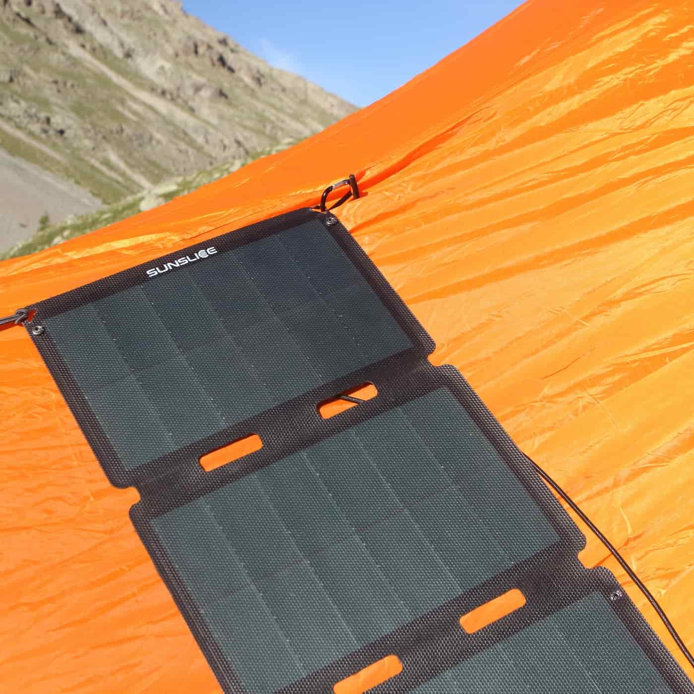 portable solar panel for camping attached to a tent on a sunny mountain