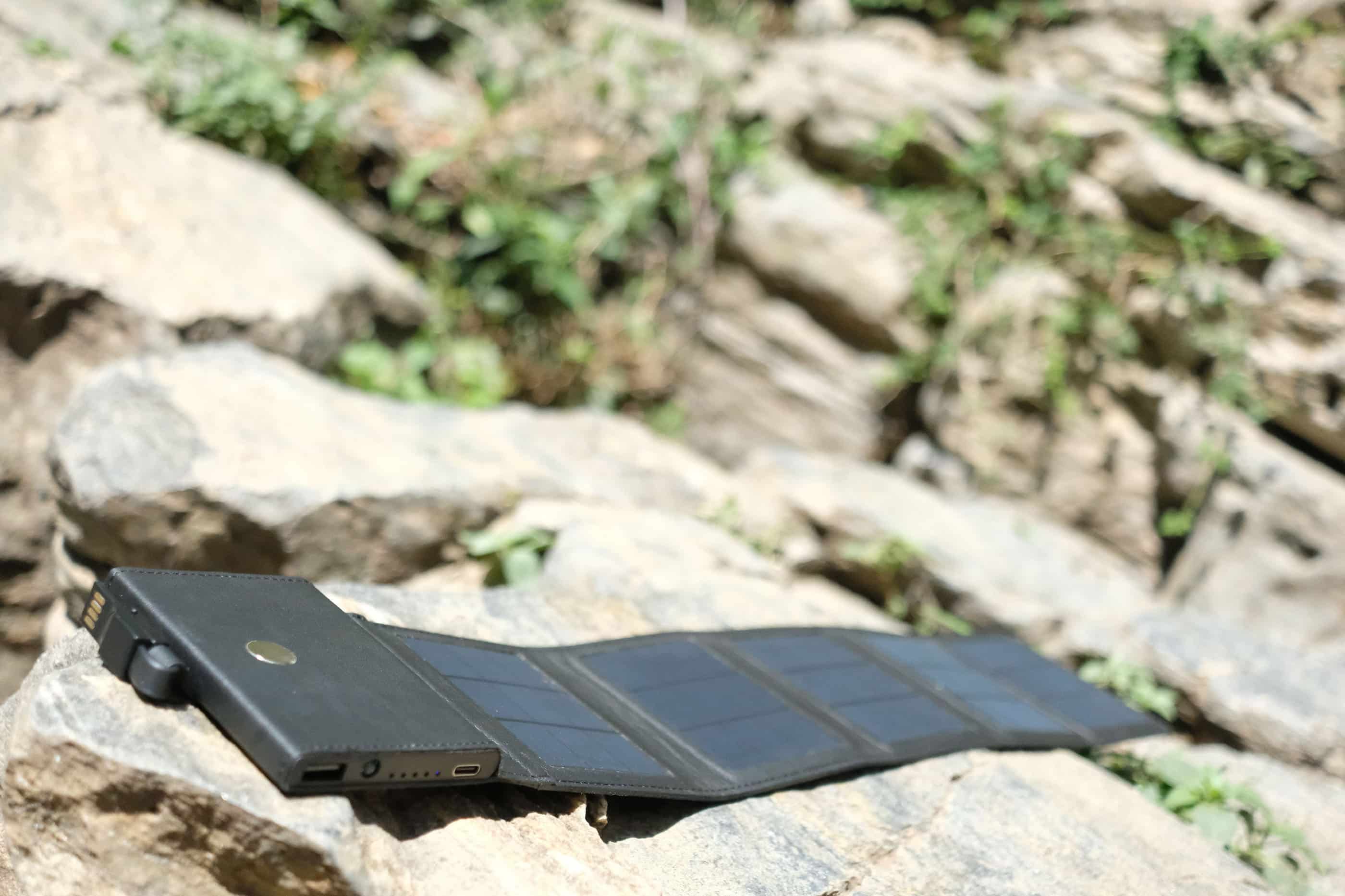 photon black power bank for camping with solar cells exposed to the sun and placed on a rock