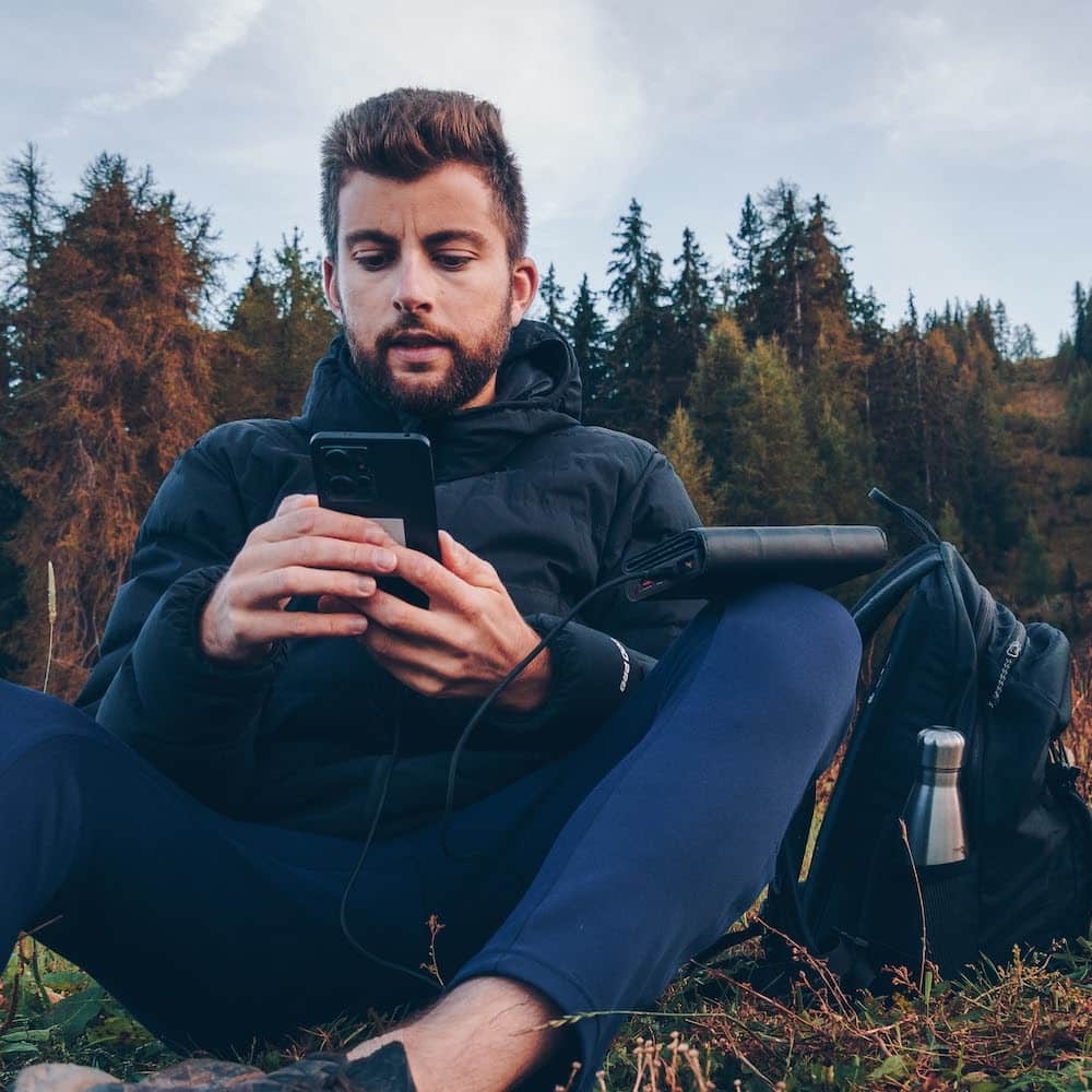 man on a hike taking a break with an electron in hand