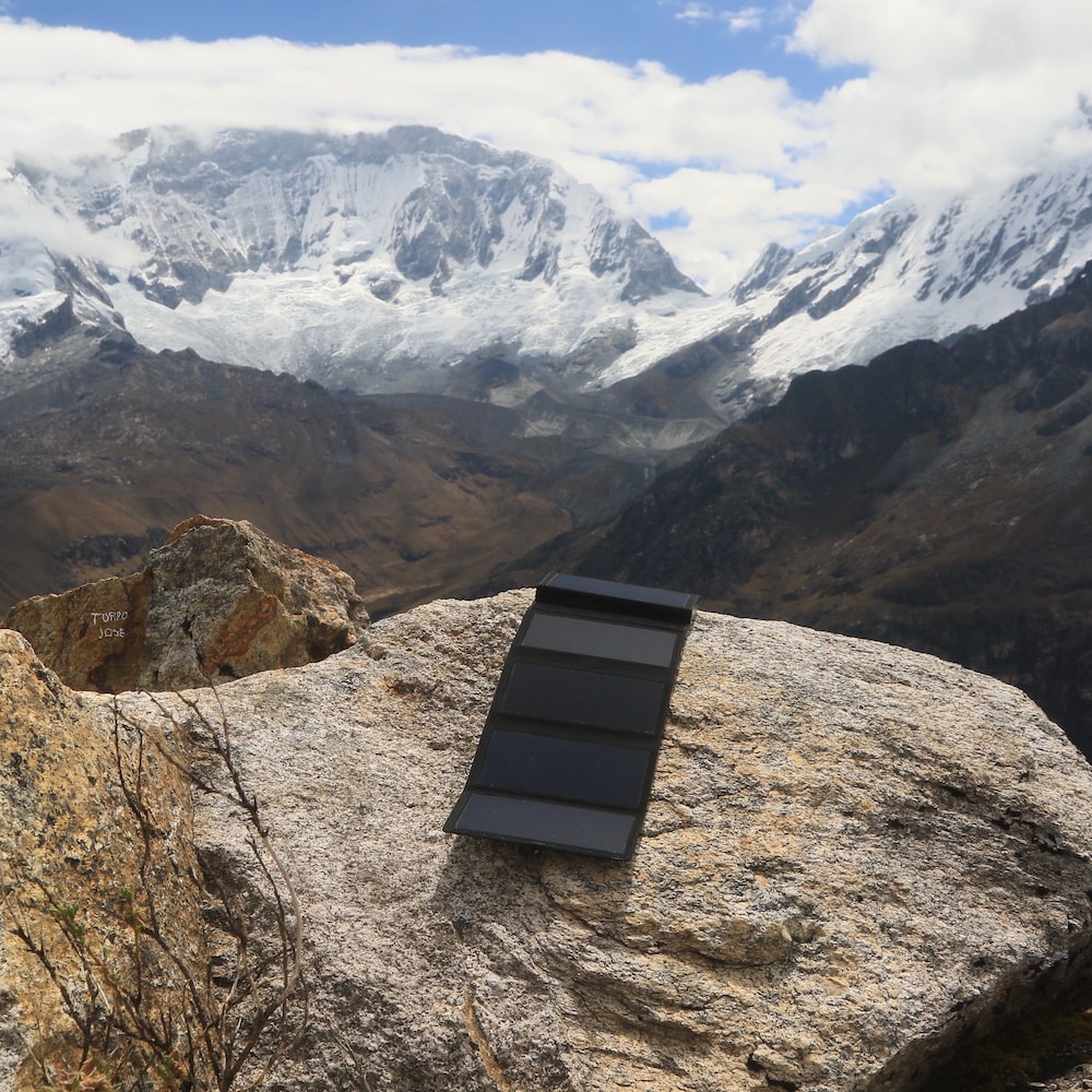 Elektronisches Solarladegerät auf einem schneebedeckten Berggipfel