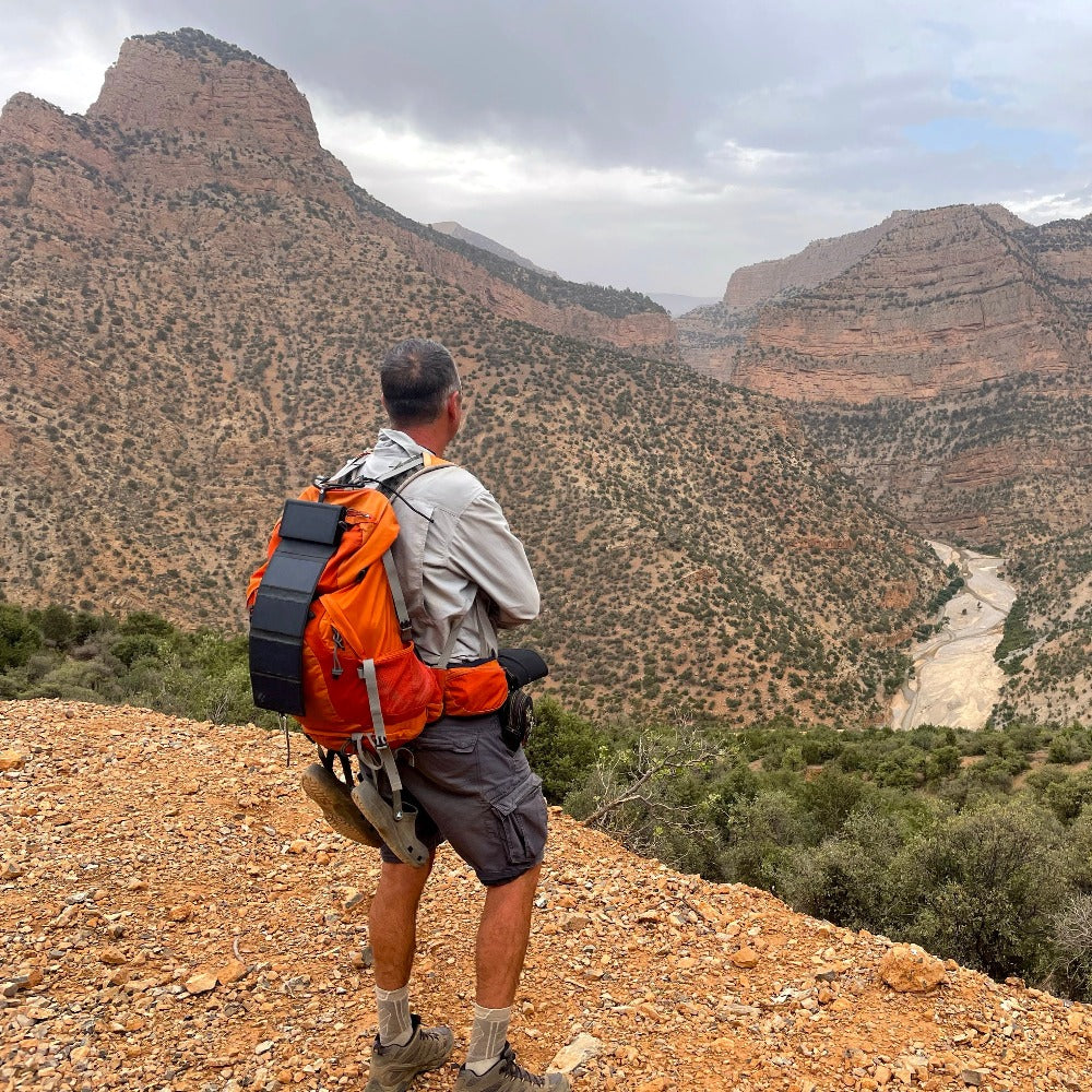 man seen from behind on a mountain with a hiking pack and the Electron