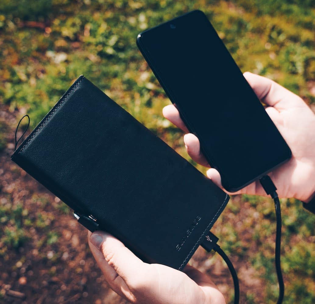 Hände, die ein geladenes smartphone einem Elektron zeigen powerbank