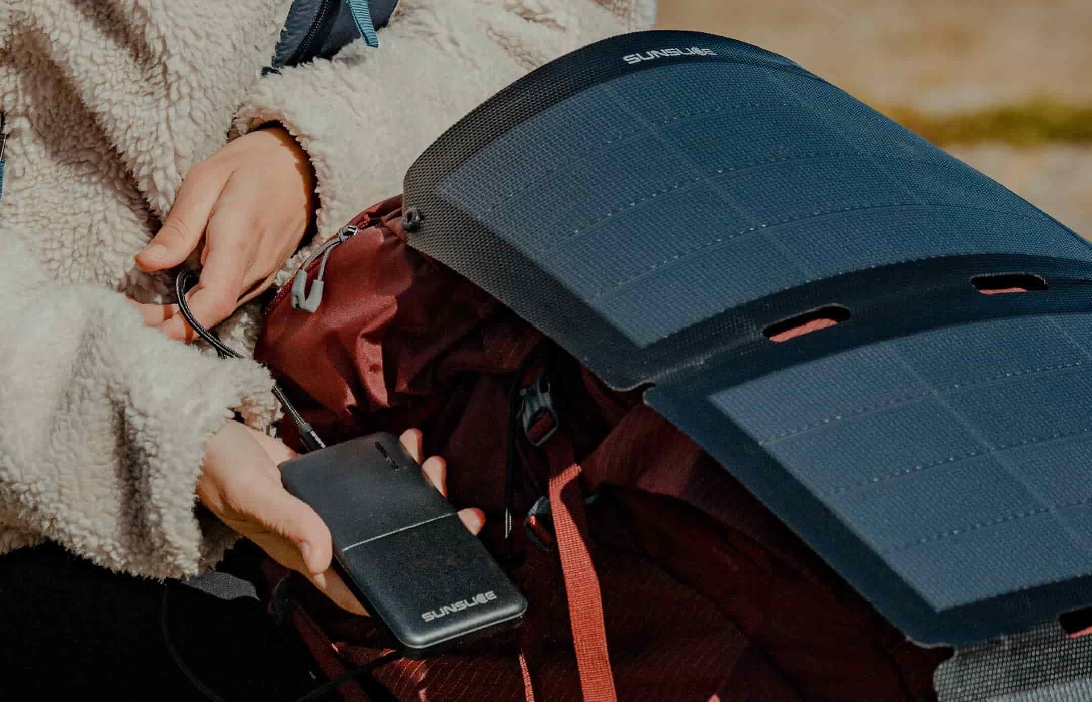 draagbaar zonnepaneel voor kamperen aangesloten op een externe batterij op een rugzak