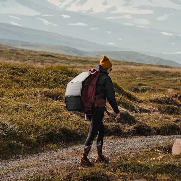 Frau beim Wandern in Island mit einem tragbaren Solarmodul Fusion Flex 24 während eines Campingausflugs