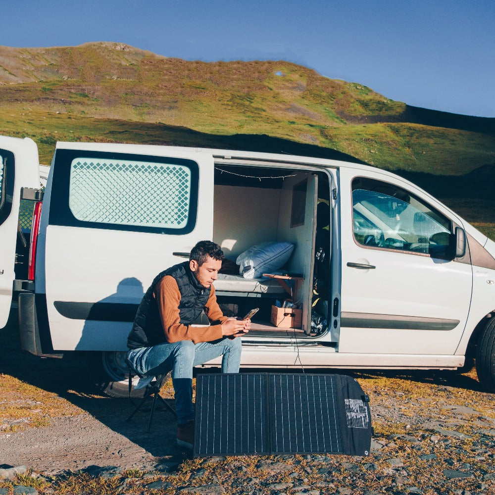 un homme avec un générateur solaire portable et son panneau solaire pour camping-car