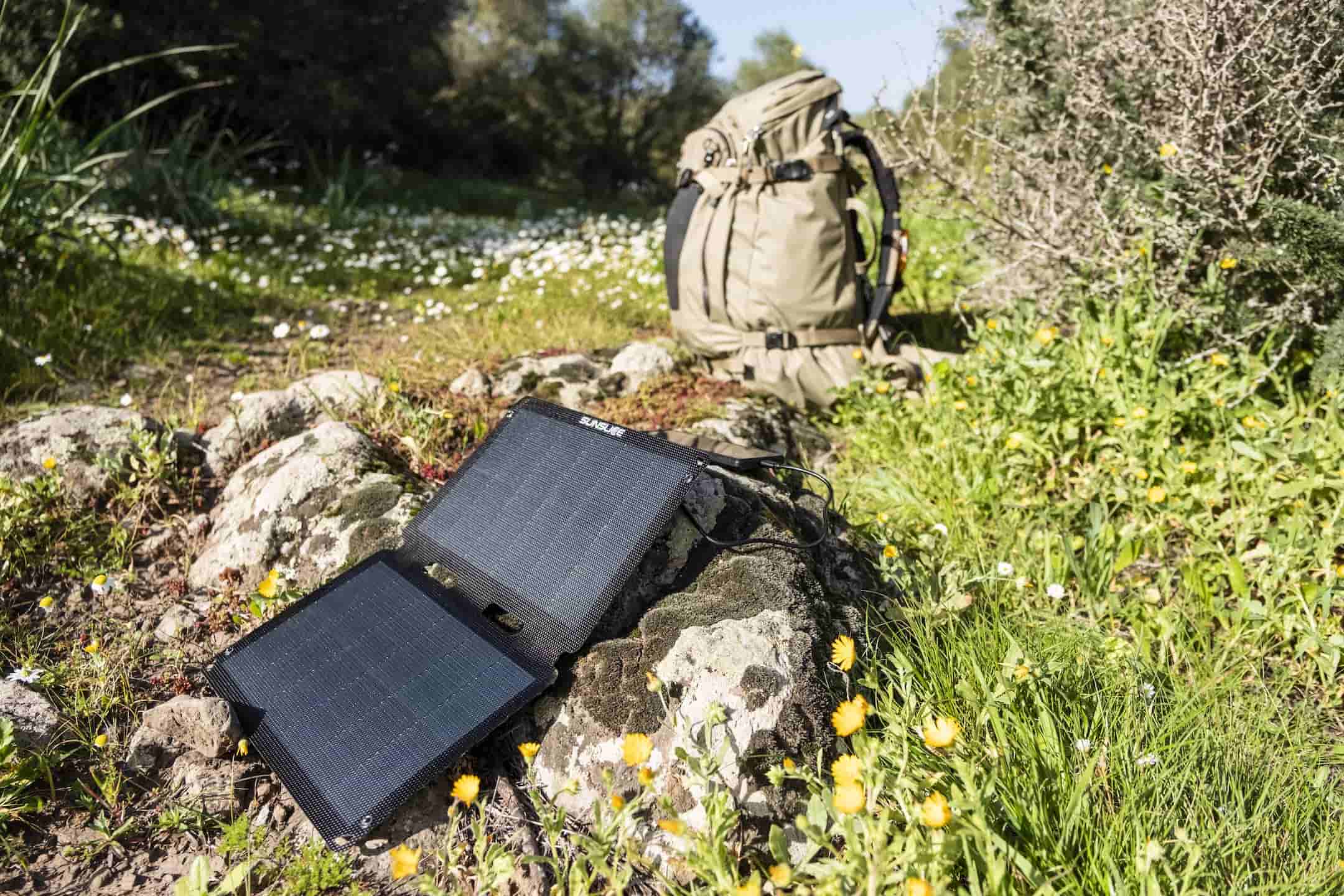 foldable solar panel Fusion Flex12 standing perpendicular to the sun on a rock with a hiking bag in the background.
