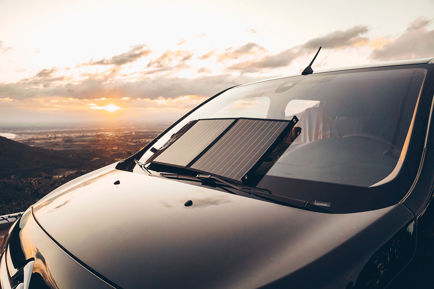 Sunslice tragbares Solarpanel an der Windschutzscheibe eines großen Autos, das der Sonne ausgesetzt ist 