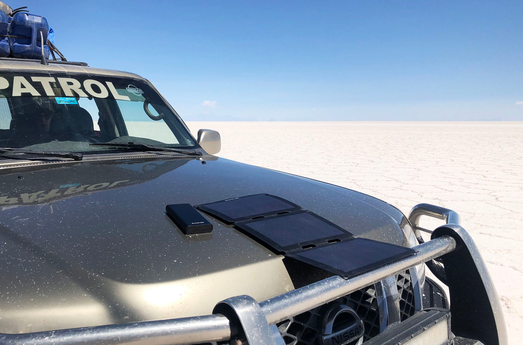 Tragbares Solarpanel (Fusion flex 18) und Powerbank (gravity 100) auf einem Auto in der Wüste 