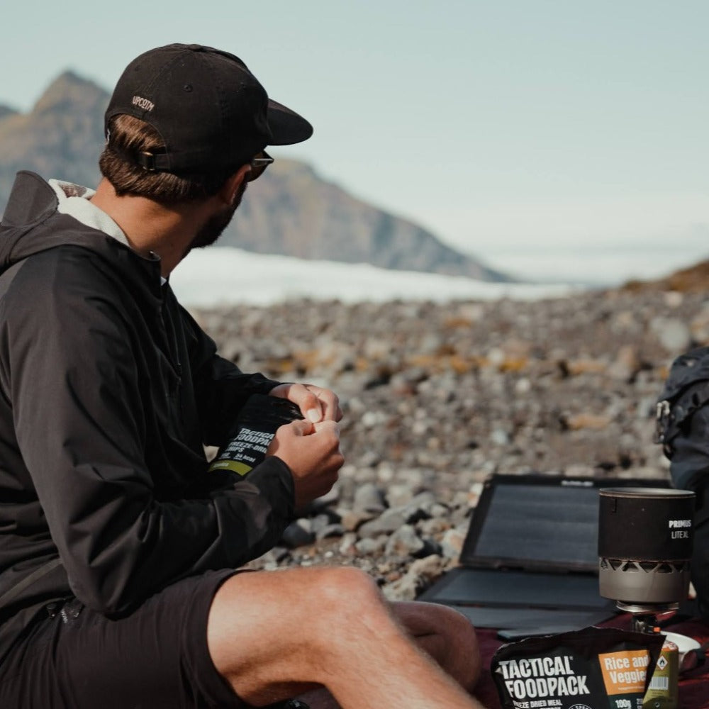 man packing up his professional photography equipment and using a compact solar panel outdoors