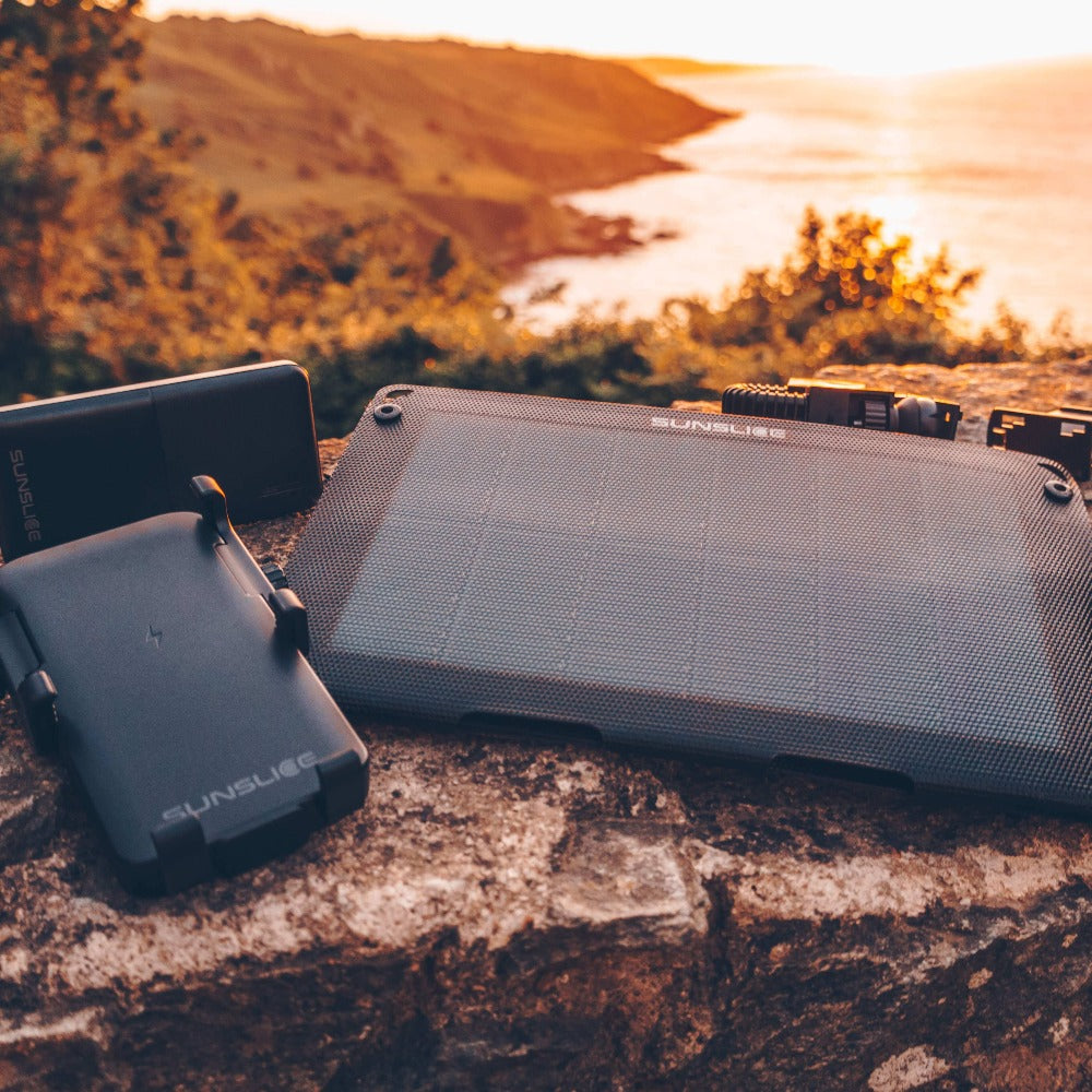 a camper on a mountaintop presenting a portable solar panel for camping with a power bank