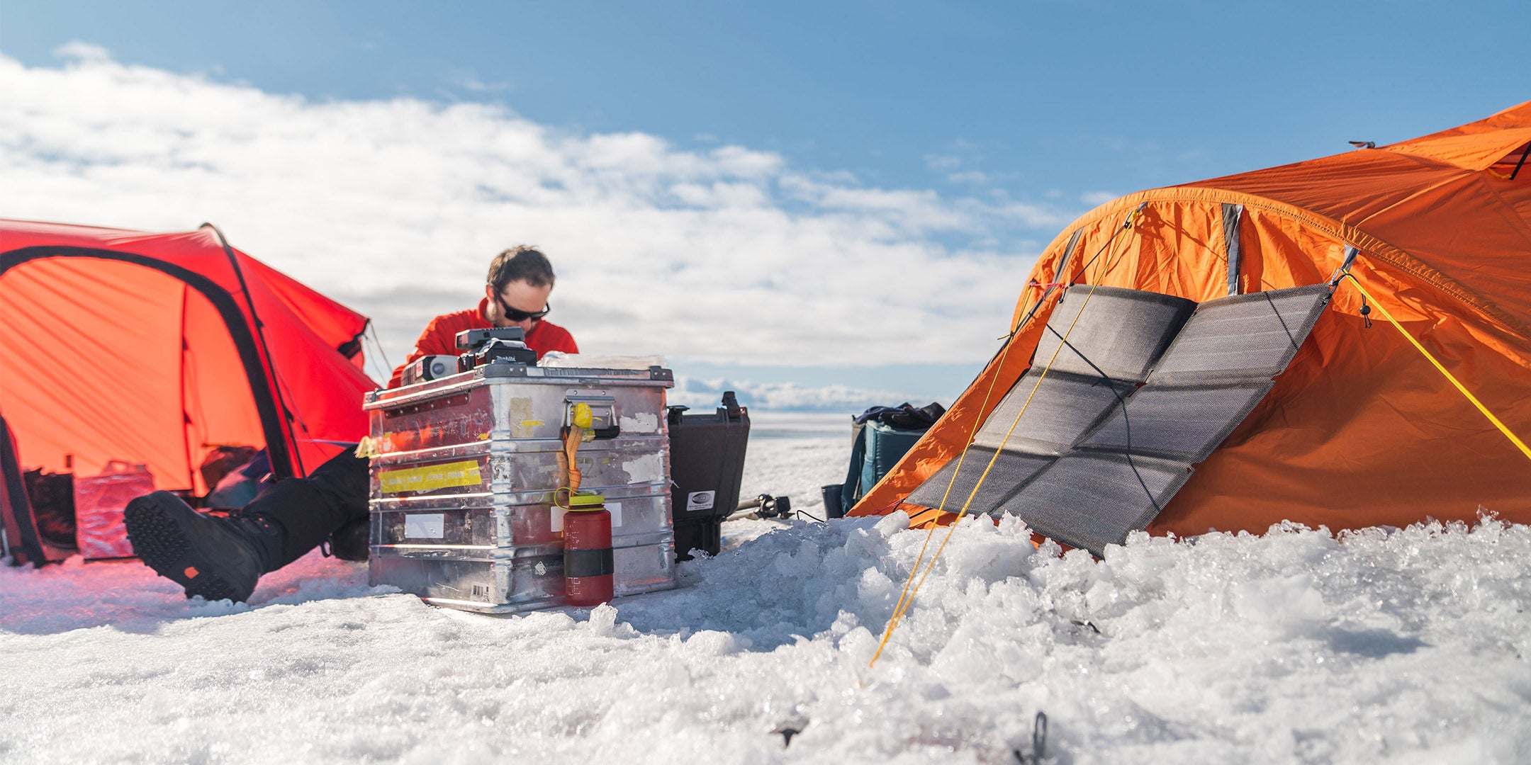 Großes flexible tragbares Solarmodul (Fusion flex 48) auf einem Zelt im Schnee (Groenland), das einen Generator auflädt 