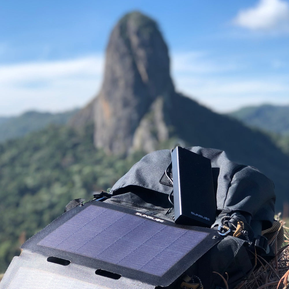Blick auf einen sonnigen Berg mit einem tragbaren Solarpanel, das an eine Powerbank 20000mah angeschlossen ist